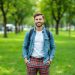 un-homme-elegant-portant-un-pantalon-en-tartan-debout-avec-assurance-dans-un-parc-de-la-ville-entoure-dherbe-verte-et-darbres-degageant-une-allure-a-la-fois-decontractee-et-a-la-mode
