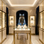 Choisir une bijouterie horlogère à Paris : les bons critères Intérieur élégant d’une bijouterie horlogère parisienne, avec des vitrines lumineuses présentant des montres raffinées et des détails en laiton sur un décor de marbre clair et de velours bleu nuit.
