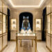 Intérieur élégant d’une bijouterie horlogère parisienne, avec des vitrines lumineuses présentant des montres raffinées et des détails en laiton sur un décor de marbre clair et de velours bleu nuit.