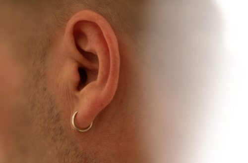Gros plan sur une oreille portant un piercing, pour illustrer la douleur selon la zone percée.